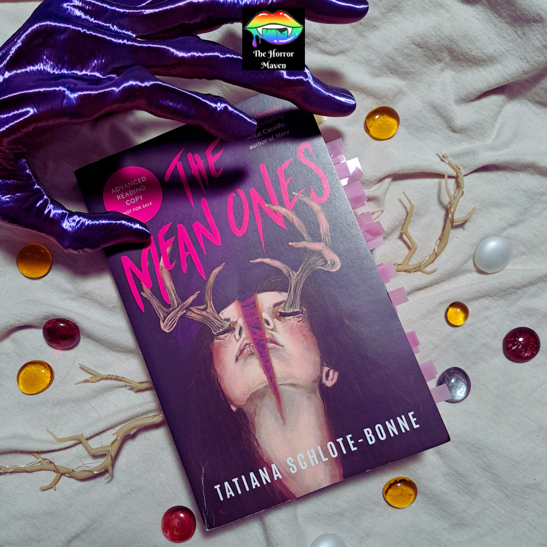 A stylized photo featuring a physical copy of "The Means" by Tatiana Schlote-Bonne with a prop hand, prop antlers, and glass beads against a white backdrop.